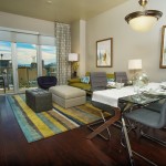 Dining room and living room in a model home at The Ogden with views of the city